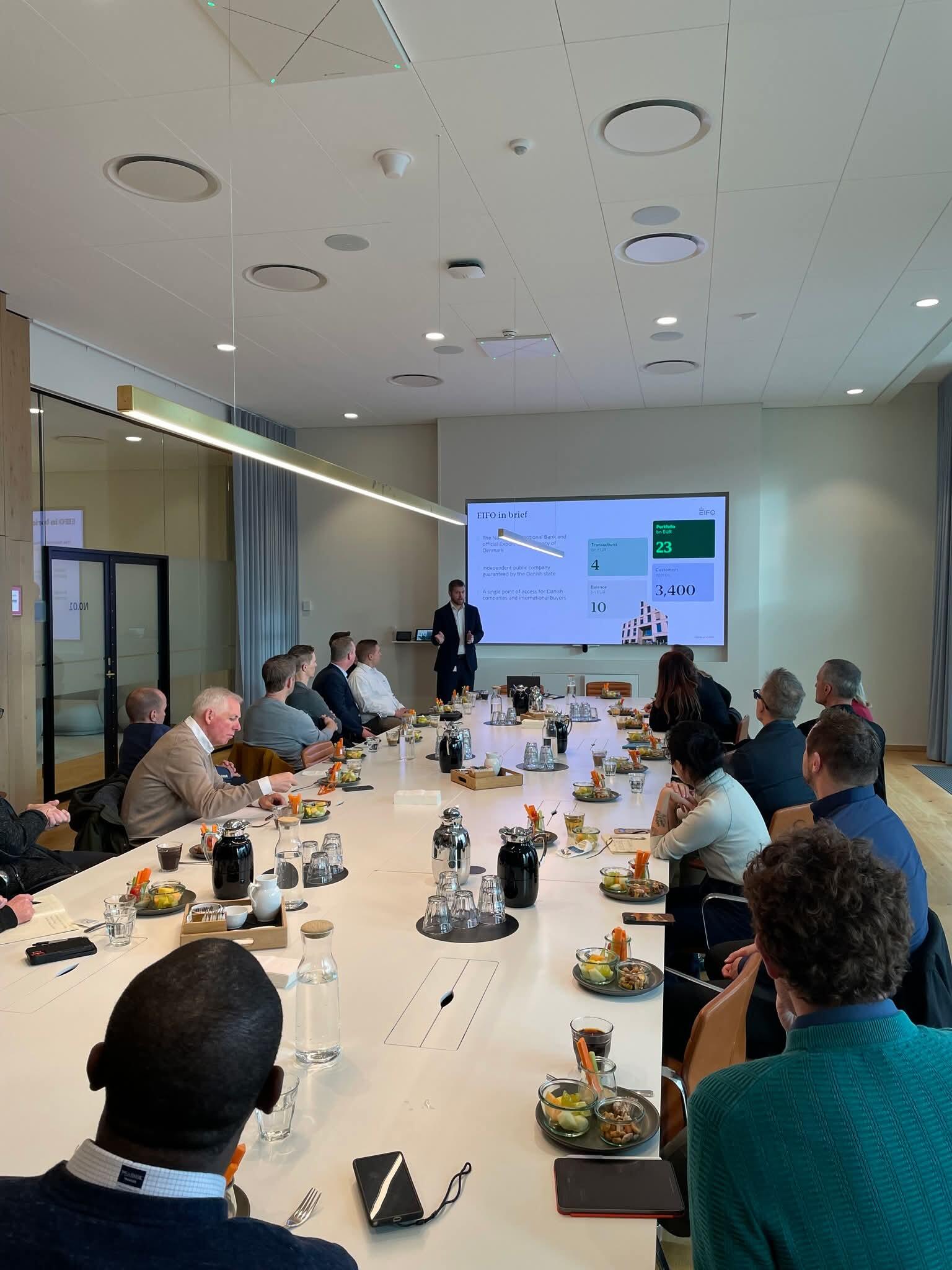 A professional trainer presenting to a group seated around a conference table